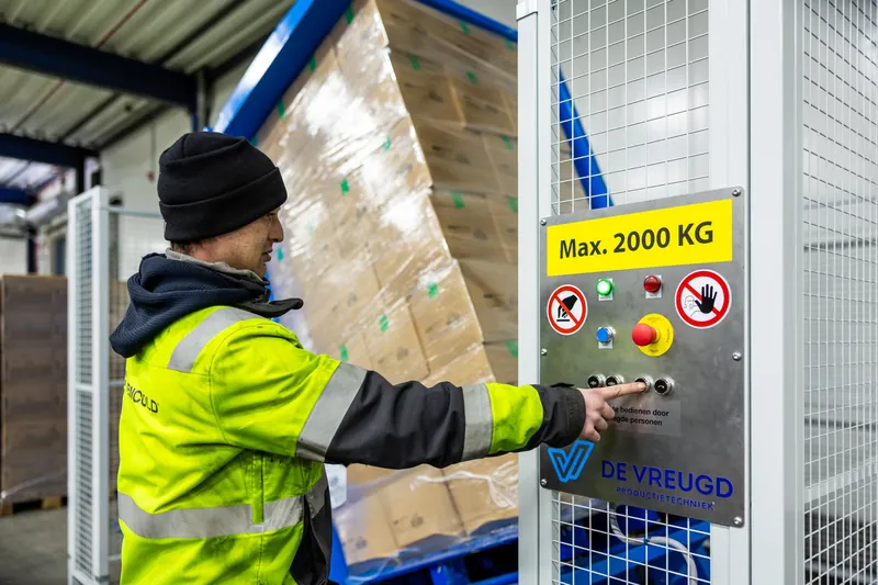Mitarbeiter bedient das Bedienfeld des PalletRotator beim Kippen einer Palette