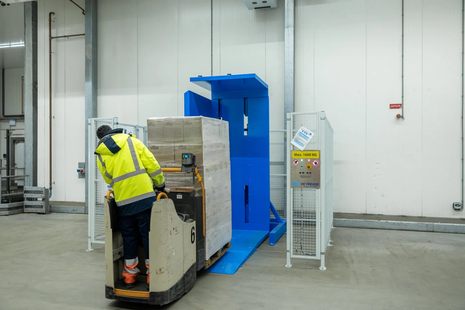 Mitarbeiter fährt mit Elektro-Hubwagen und Palette auf die Rampe des Palettenwenders PalletRotator EPT
